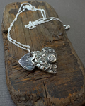 Silver double heart necklace with a silver chain on a driftwood block