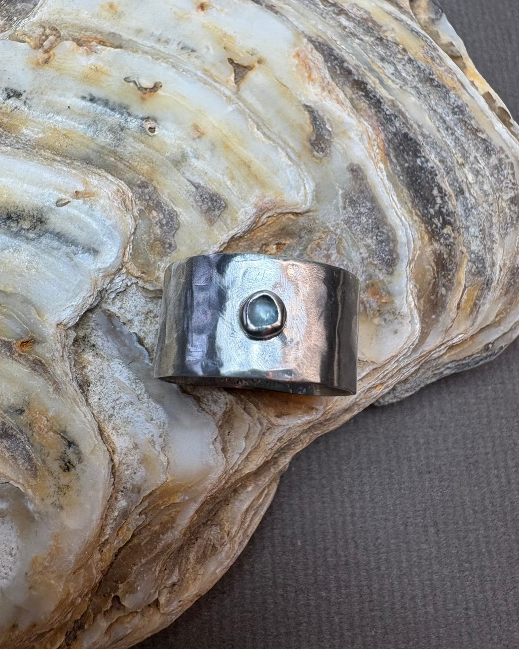 Silver ring with a topaz stone on a large oyster shell