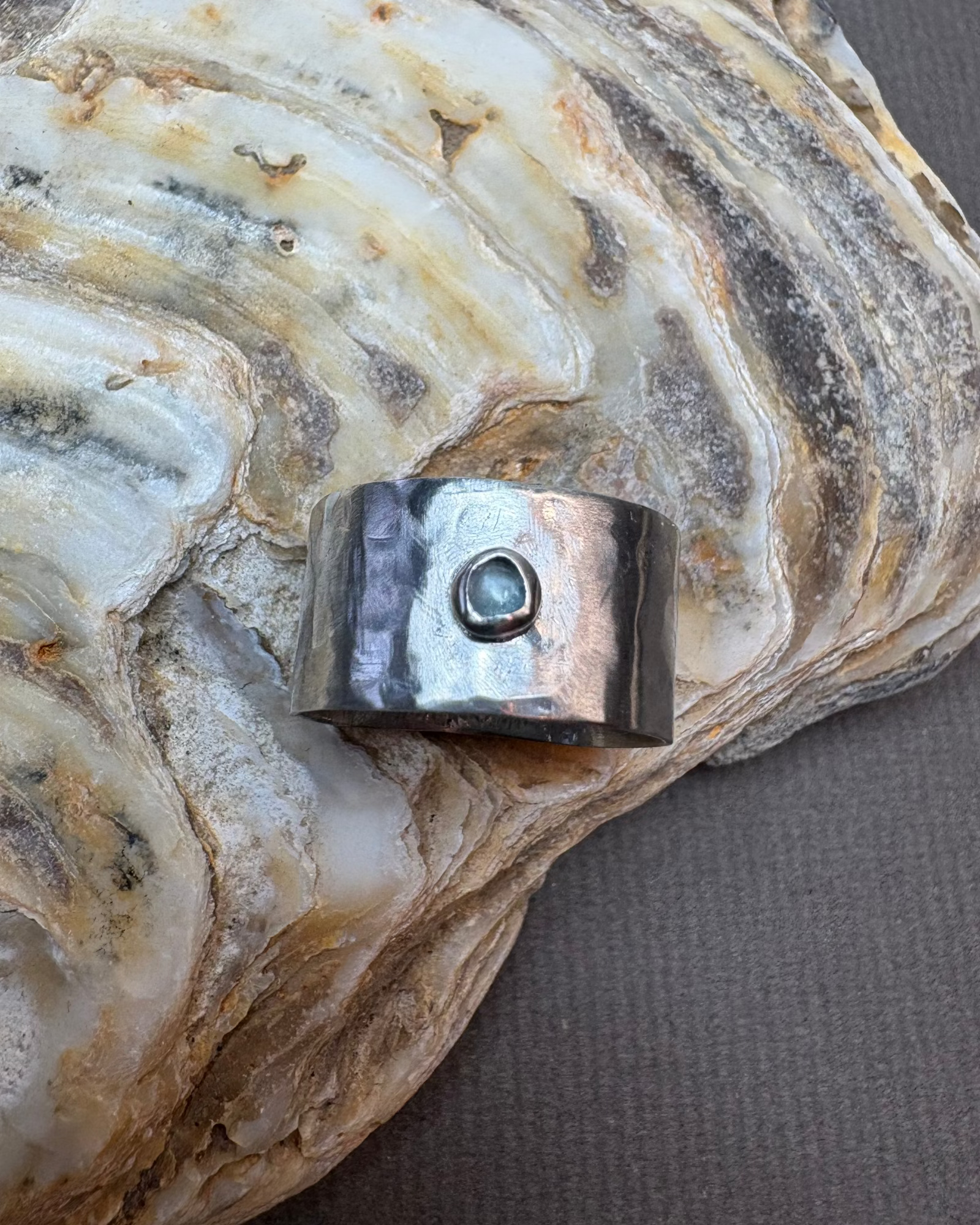 Silver ring with a topaz stone on a large oyster shell