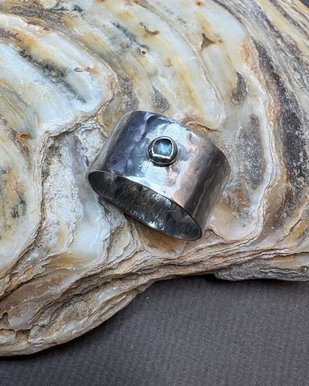 Silver ring with a topaz gemstone on a textured stone surface