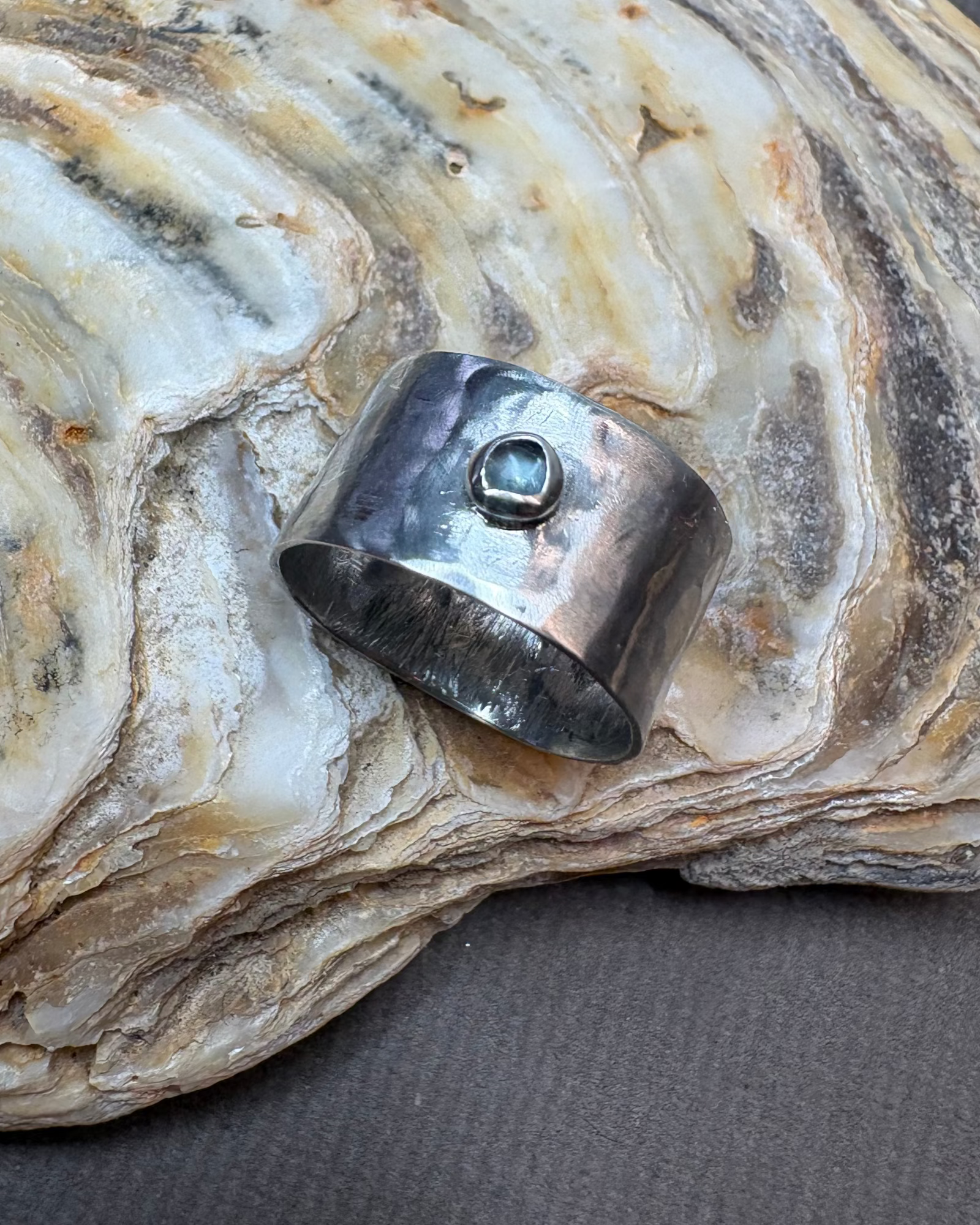 Silver ring with a topaz gemstone on a textured stone surface