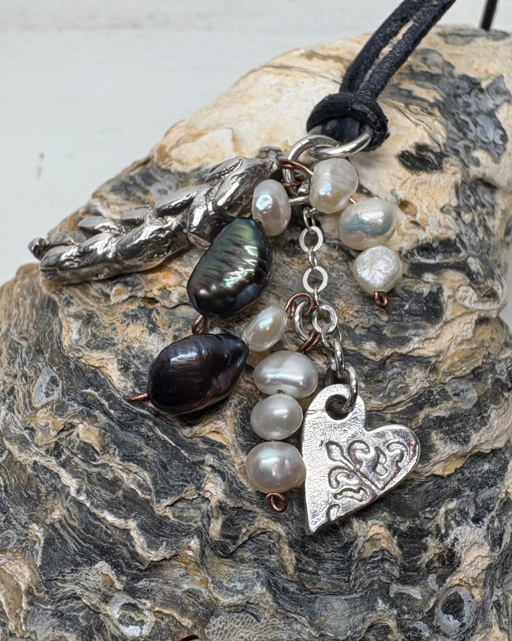 Necklace with heart charms and pearls on a textured shell surface