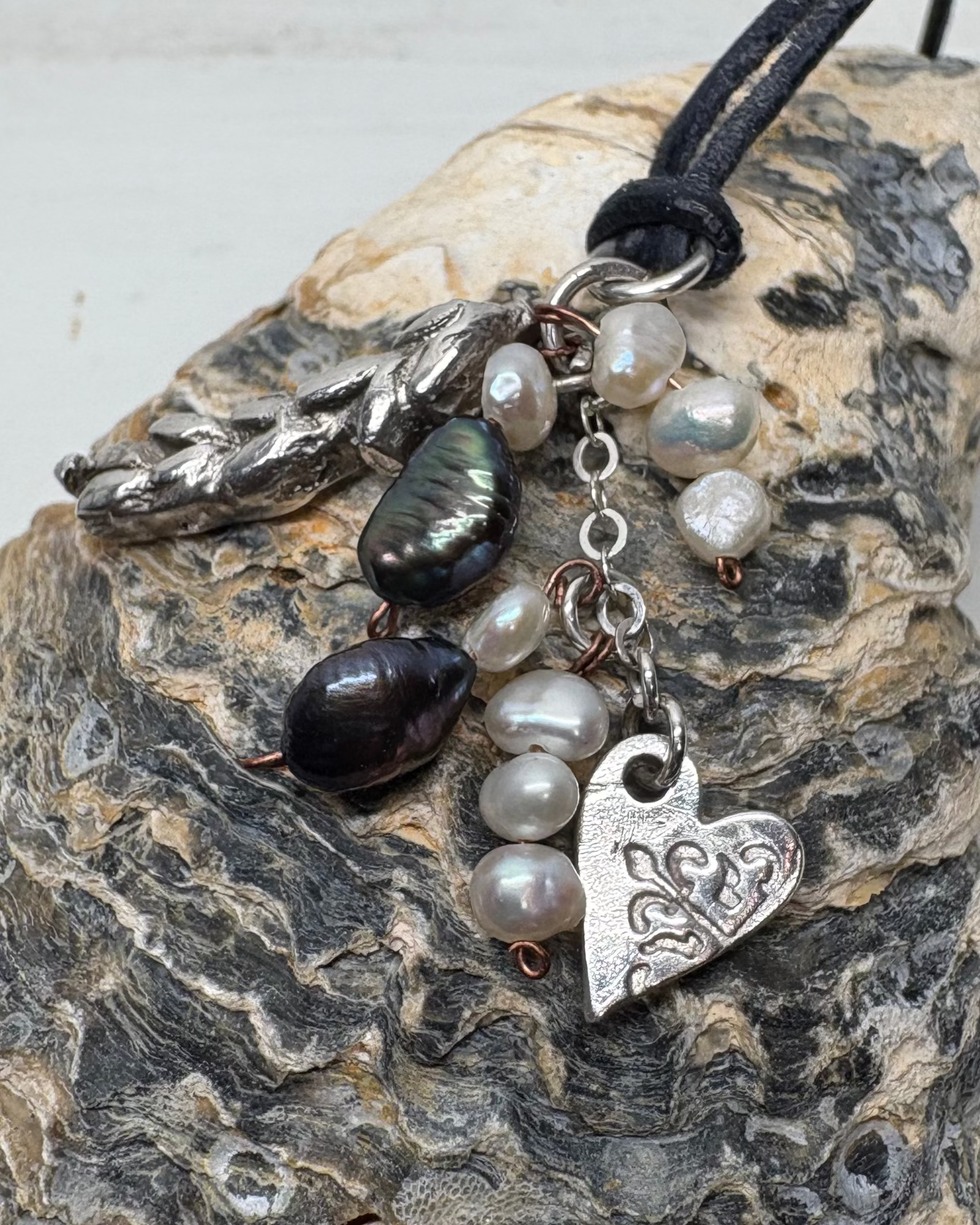 Necklace with heart charms and pearls on a textured shell surface