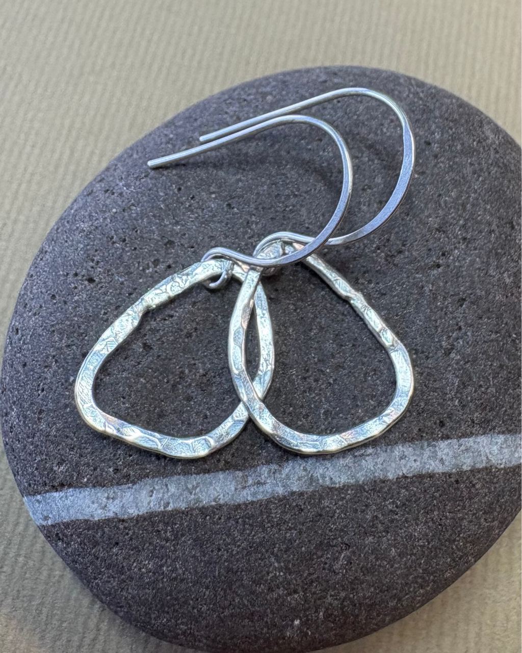 Silver hoop earrings on a dark stone surface