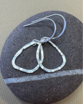 Silver hoop earrings on a dark stone surface