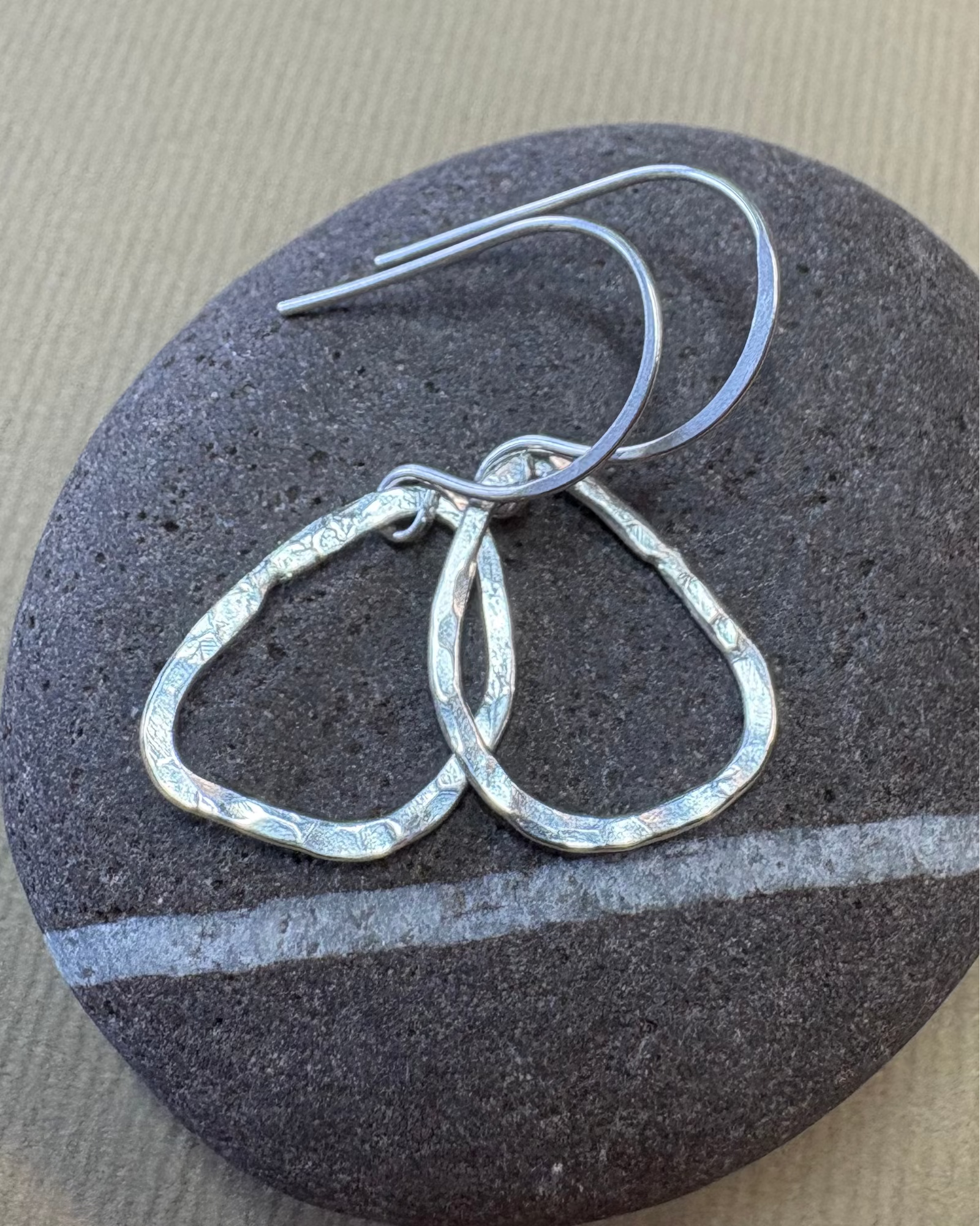Silver hoop earrings on a dark stone surface