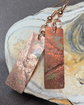 Copper earrings with pressed texture and pale green oxidisation patterns with rose gold ear wires with shell background