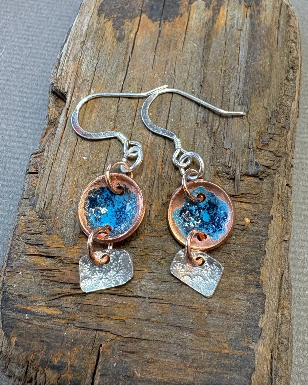 Pair of copper and silver earrings with blue enamel a driftwood surface