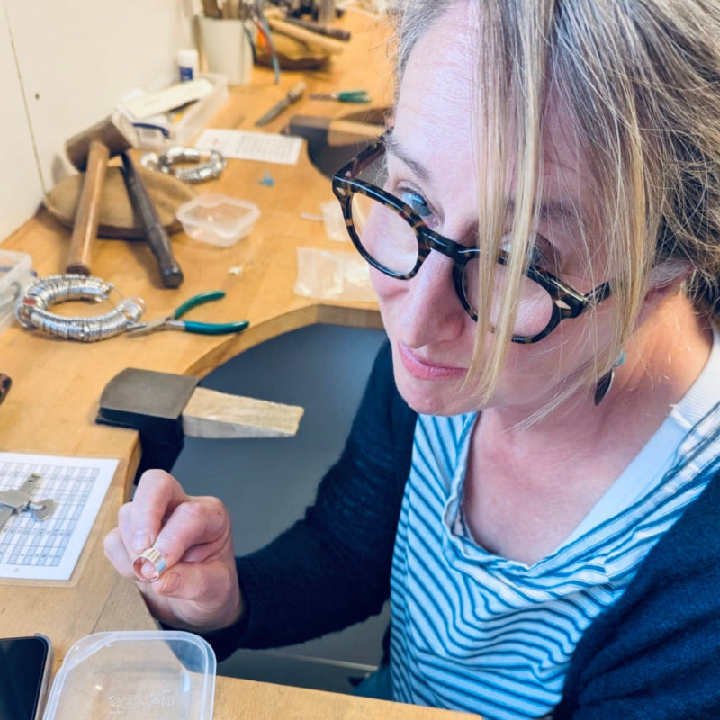 Julia working on jewellery in a silver smith class with tools and materials around