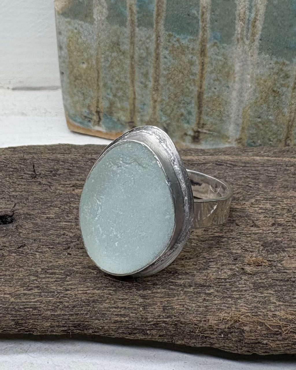 Silver ring with aqua sea glass on a driftwood surface