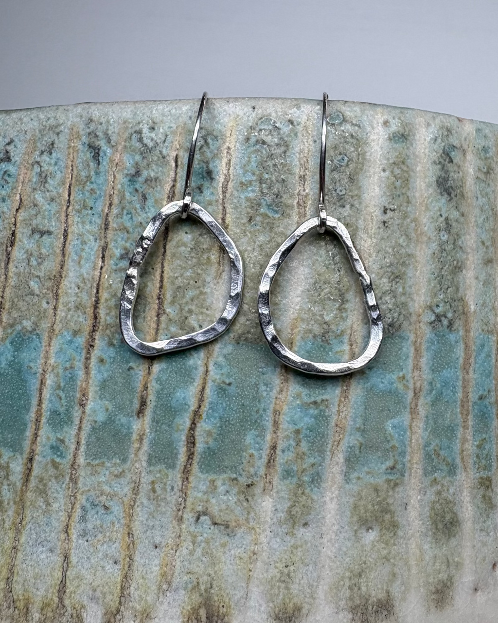 Hammered Silver earrings on a ceramic surface