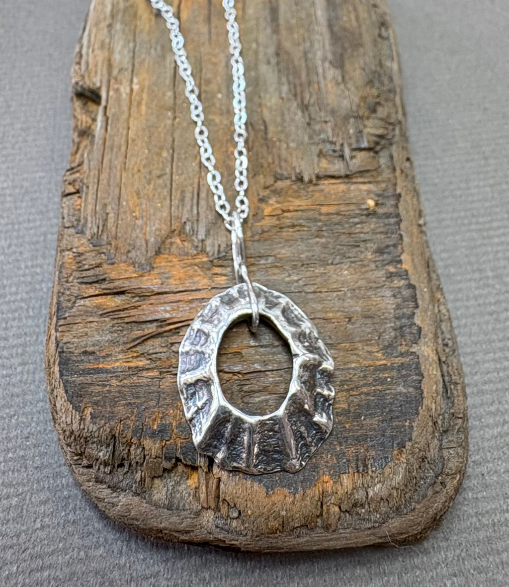 Silver sea worn limpet necklace on a driftwood block