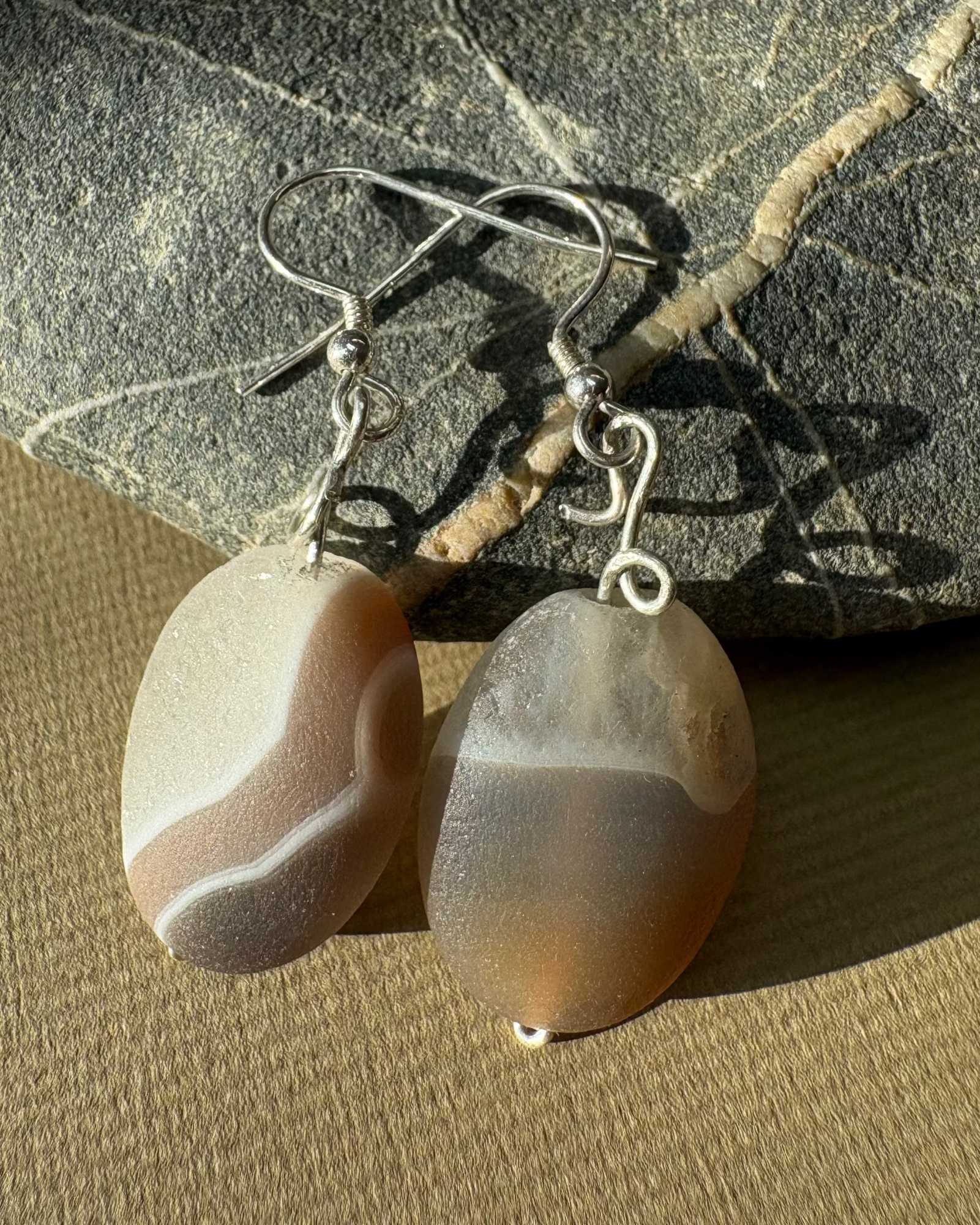 Pair of agate geode earrings on a textured stone surface