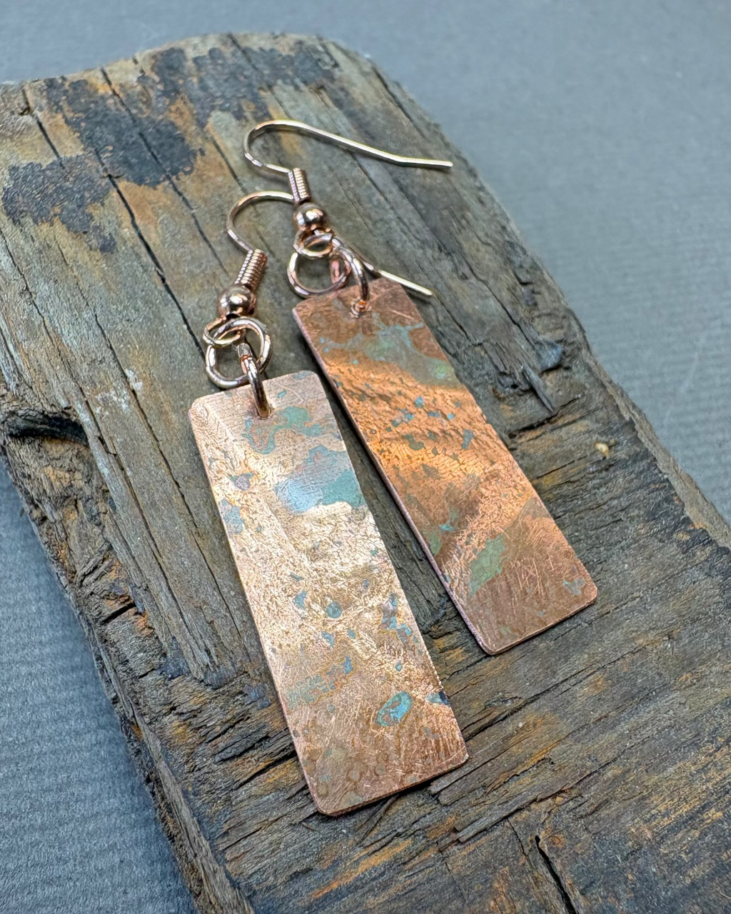 Pair of oxidised copper texture earrings on a textured driftwood surface 