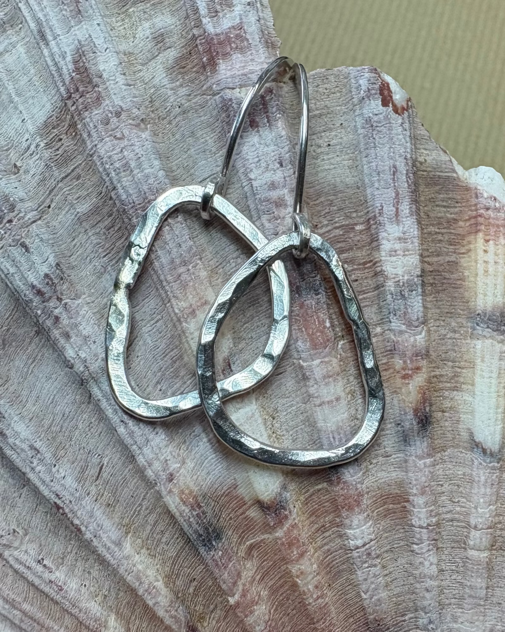 Silver hammered hoop earrings on a shell
