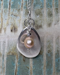 Necklace with a teardrop-shaped pendant featuring a pearl on a textured surface.