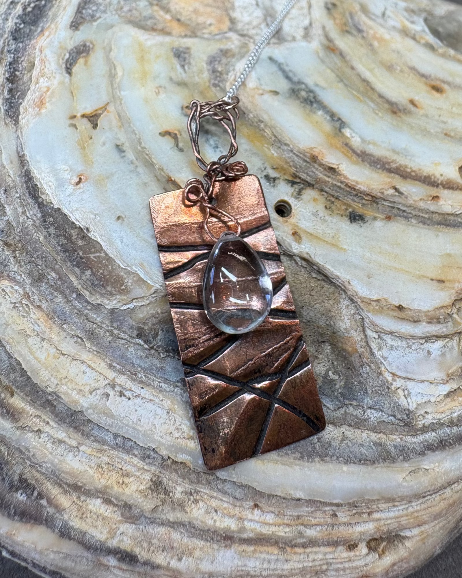 Copper pendant with a quartz crystal on a shell surface