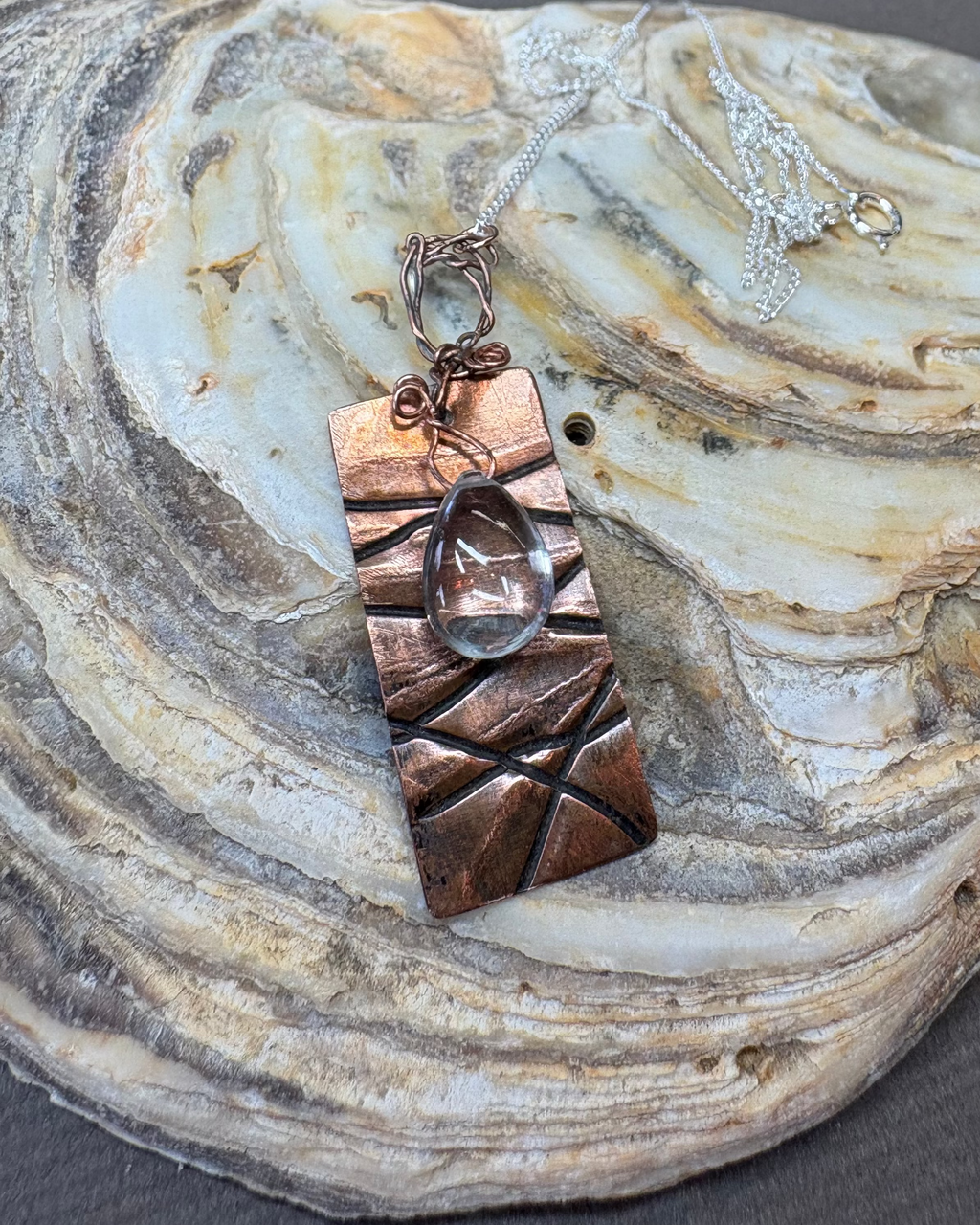 Copper texture oxidised pendant with quartz droplet on an oyster shell