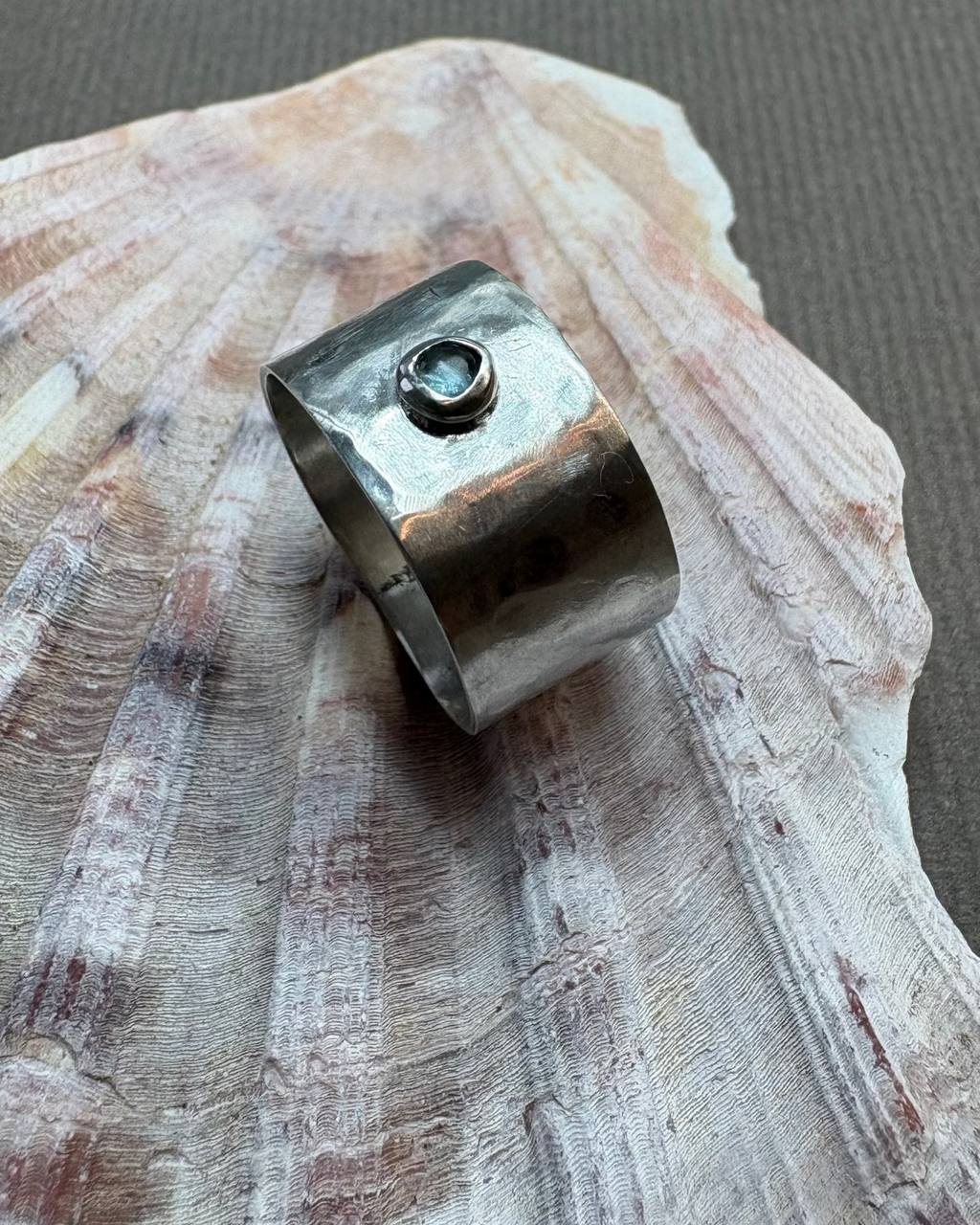 Hammered silver ring set with a topaz cabochon on a shell background