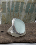 Silver ring set with aqua sea glass on a driftwood surface