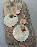 Pair of copper and turquoise oxidised earrings with unakite beads on a piece of driftwood