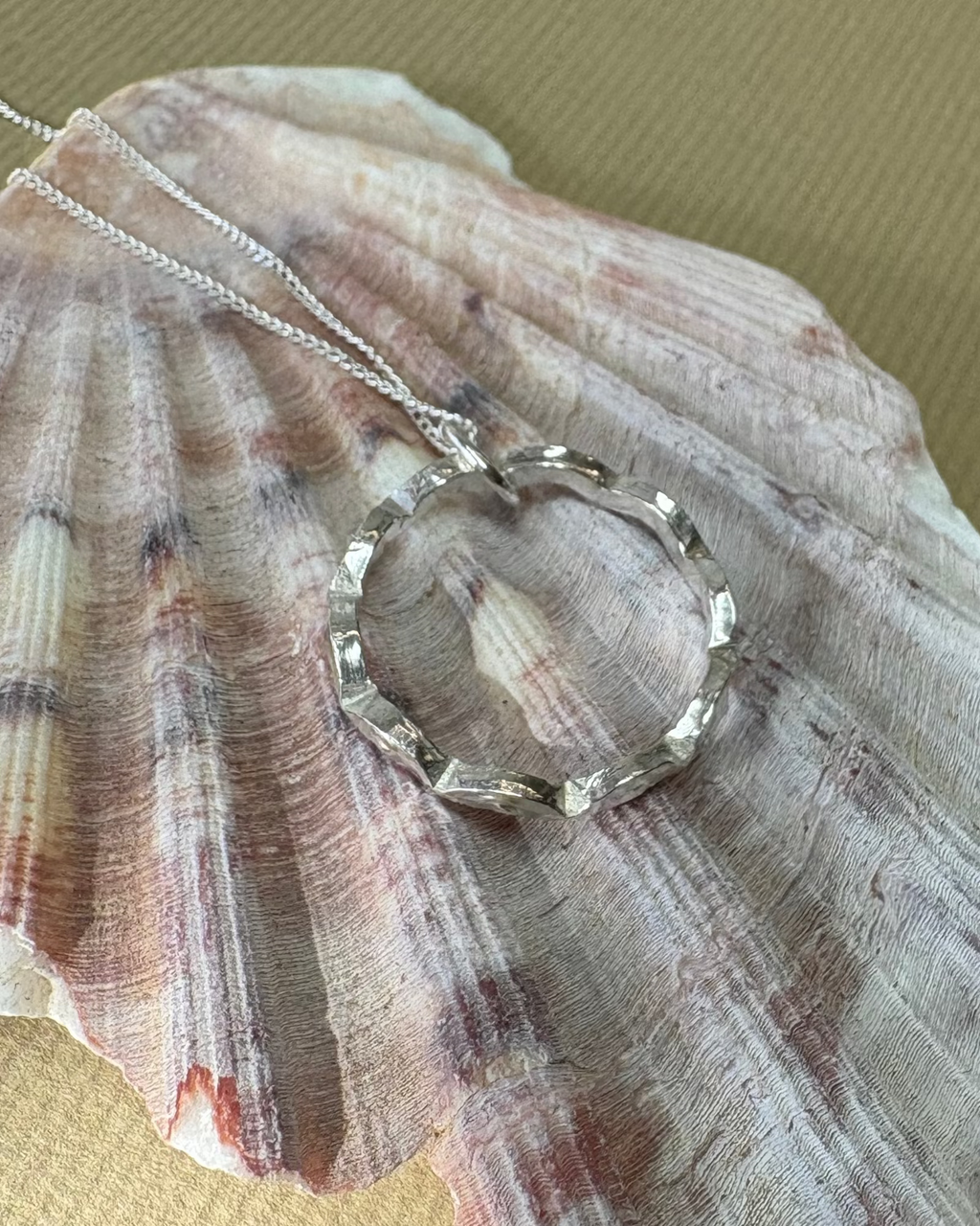 Necklace with a circular wavy pendant on a large shell against a gold background
