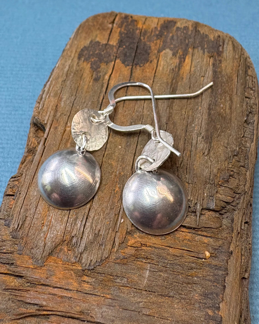 back of the round silver concave enamel disc earrings with blue, aqua and silver to look like pools, with second hammered silver circle disk above, hung on silver ear wires